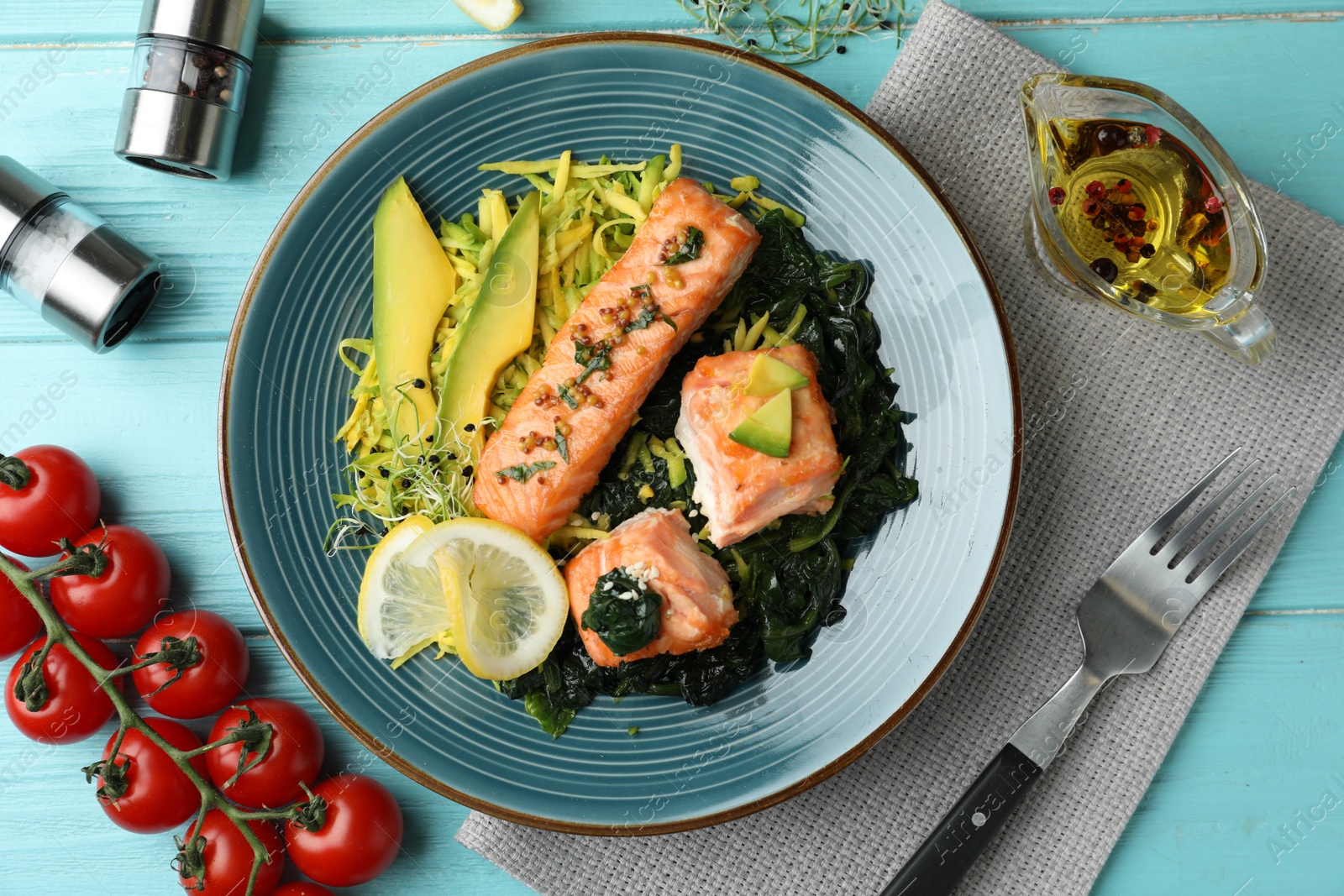 Photo of Tasty salmon with spinach served on blue wooden table, flat lay