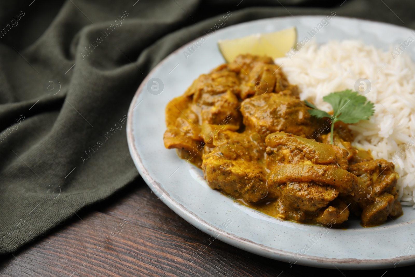 Photo of Delicious chicken curry with rice on wooden table, closeup