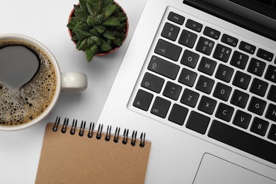 Photo of Modern laptop, notebook, houseplant and cup of coffee on white background, flat lay