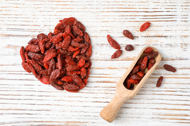 Photo of Dried goji berries on white wooden table, flat lay