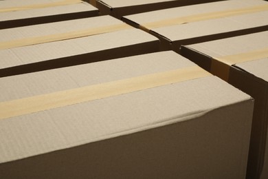Photo of Many closed cardboard boxes with tape as background, closeup