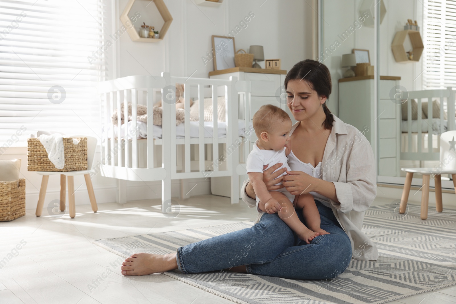 Photo of Happy young mother with her baby in nursery. Space for text