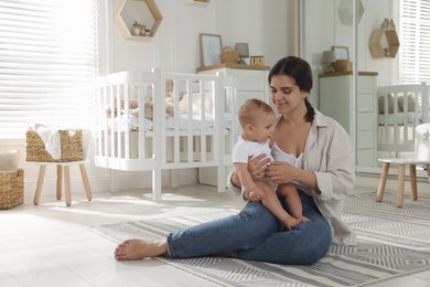 Photo of Happy young mother with her baby in nursery. Space for text