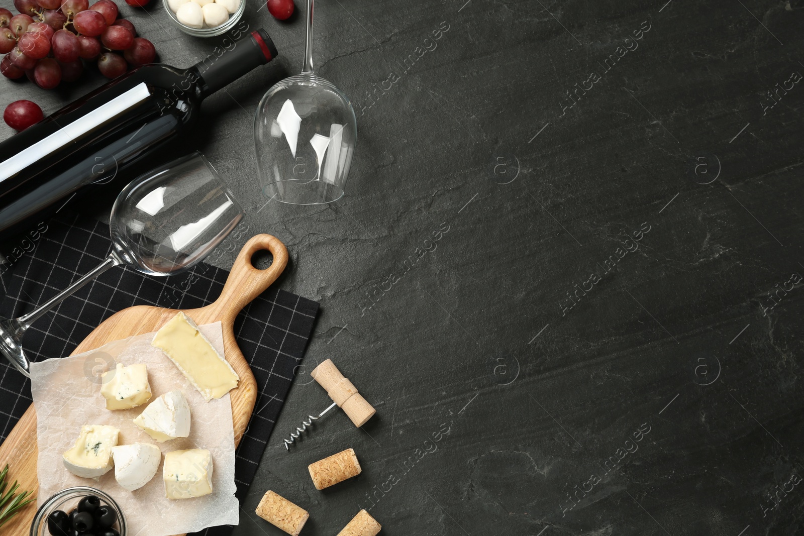 Photo of Flat lay composition with red wine and snacks on black table, space for text