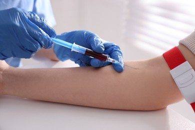 Doctor drawing blood sample of patient with syringe in hospital, closeup