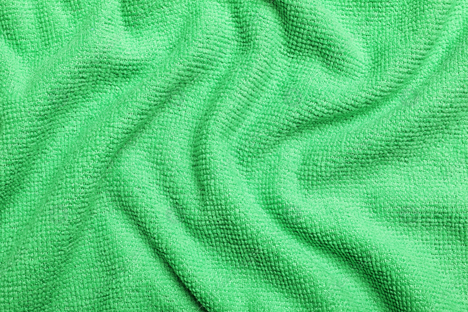 Photo of Crumpled light green microfiber cloth as background, closeup