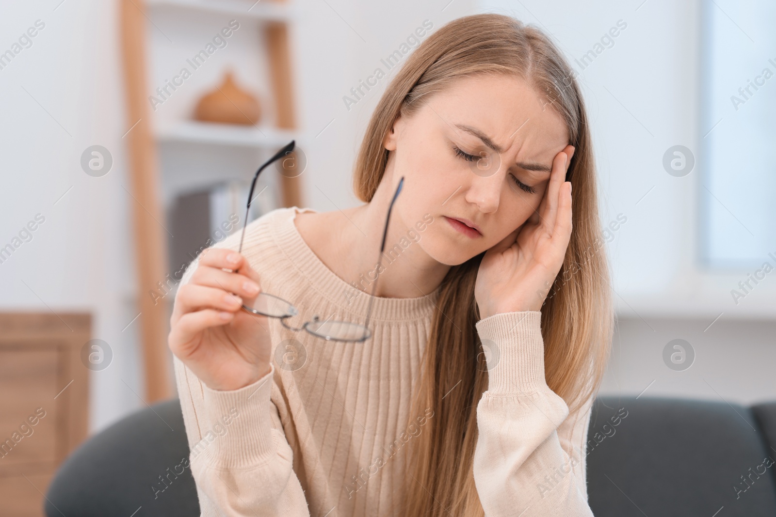 Photo of Overwhelmed young woman with glasses suffering from headache at home