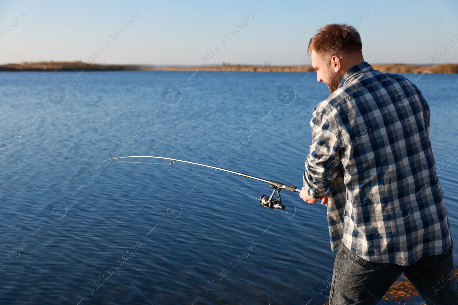 Photo of Fisherman with rod fishing at riverside. Recreational activity