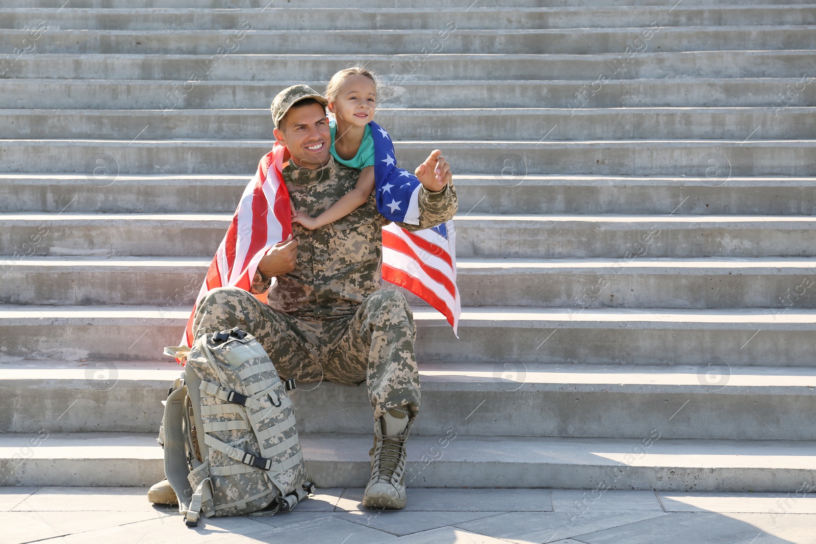 Photo of Soldier with flag of USA and his little daughter outdoors, space for text