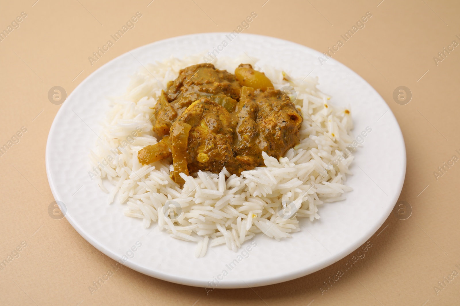 Photo of Delicious chicken curry with rice on beige background, closeup