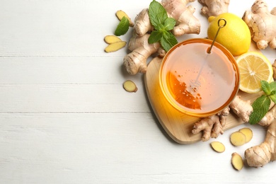 Photo of Ginger, honey and lemon on white wooden table, flat lay with space for text. Natural cold remedies