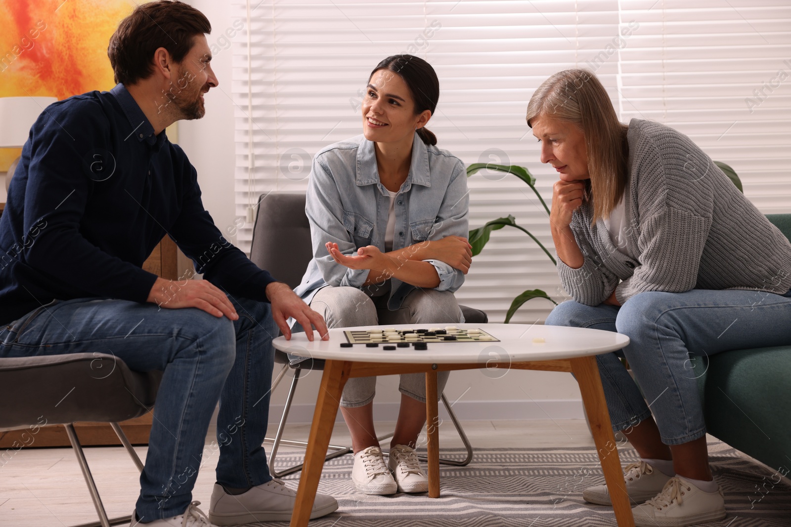 Photo of Family playing checkers at coffee table in room