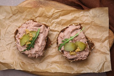 Delicious liverwurst sandwiches with pickled cucumber and mustard on grey table, top view