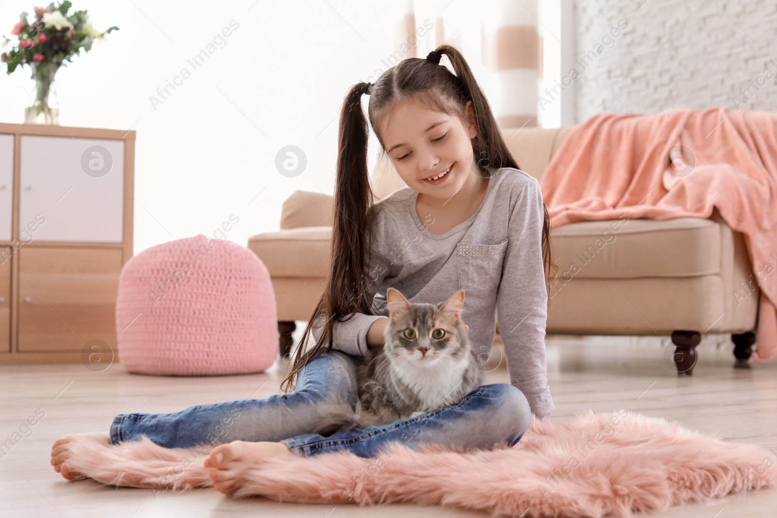 Photo of Cute little girl with cat sitting on floor at home