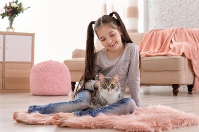 Photo of Cute little girl with cat sitting on floor at home