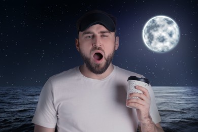 Image of Tired young man with cup of coffee and beautiful seascape with full moon in night sky on background