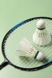 Feather badminton shuttlecocks and racket on green background, above view