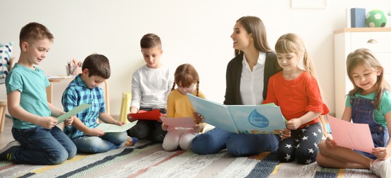 Image of Cute little children with teacher in classroom at school. Banner design