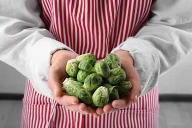 Photo of Woman holding pile of fresh green brussels sprouts, closeup