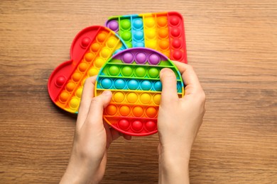 Photo of Woman using pop it fidget toy at wooden table, top view