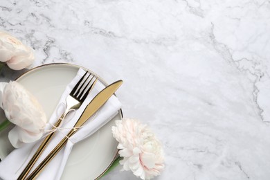 Photo of Stylish table setting with cutlery and flowers on white marble background, flat lay. Space for text