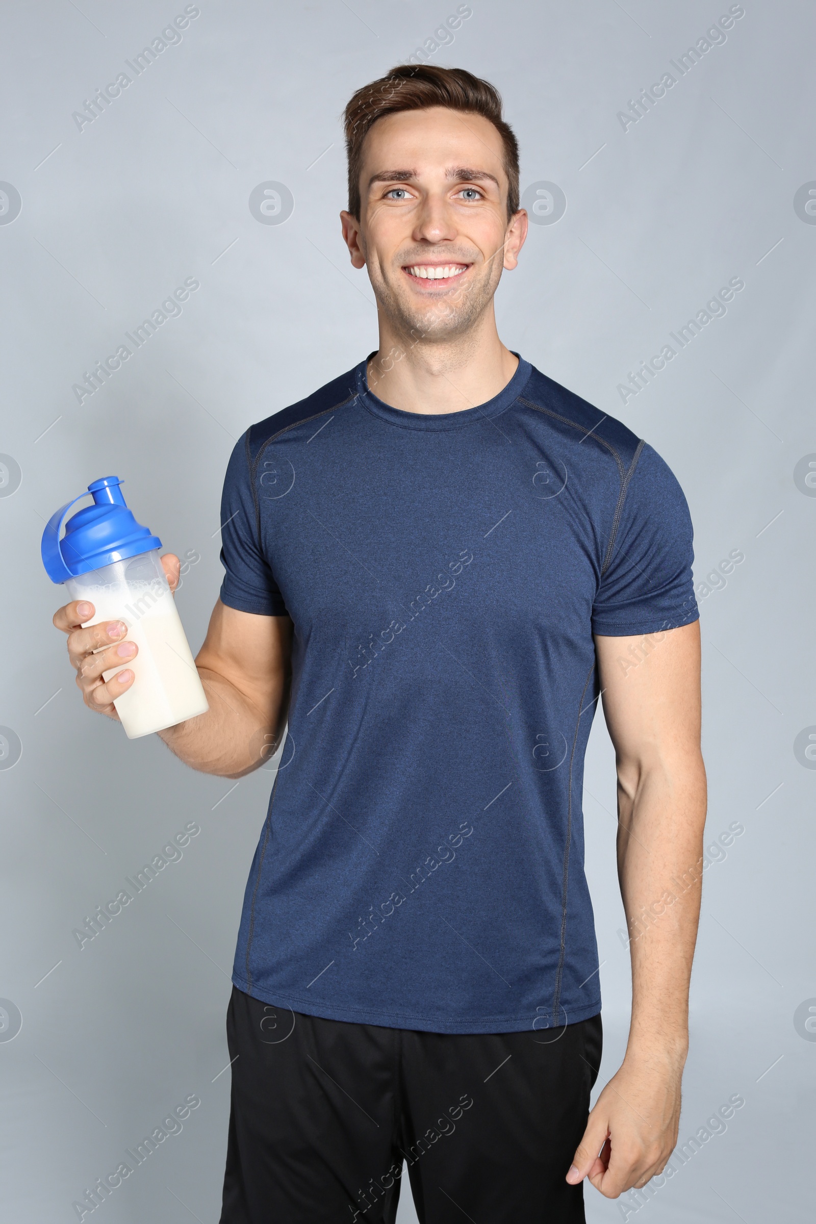 Photo of Portrait of man with bottle of protein shake on color background