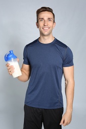 Portrait of man with bottle of protein shake on color background