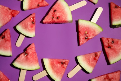 Photo of Frame of watermelon slices with wooden sticks on purple background, flat lay. Space for text