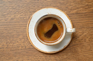 Photo of Cup of aromatic coffee on wooden table, top view