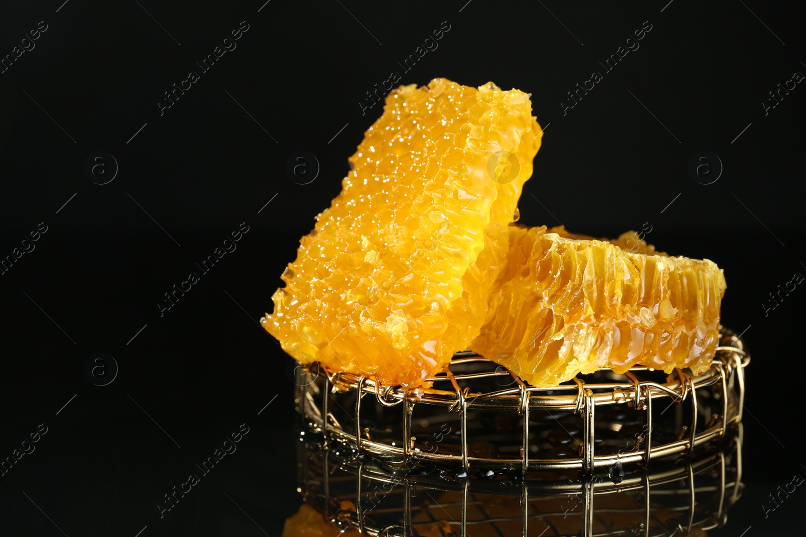 Photo of Natural honeycombs with tasty honey on black background, space for text
