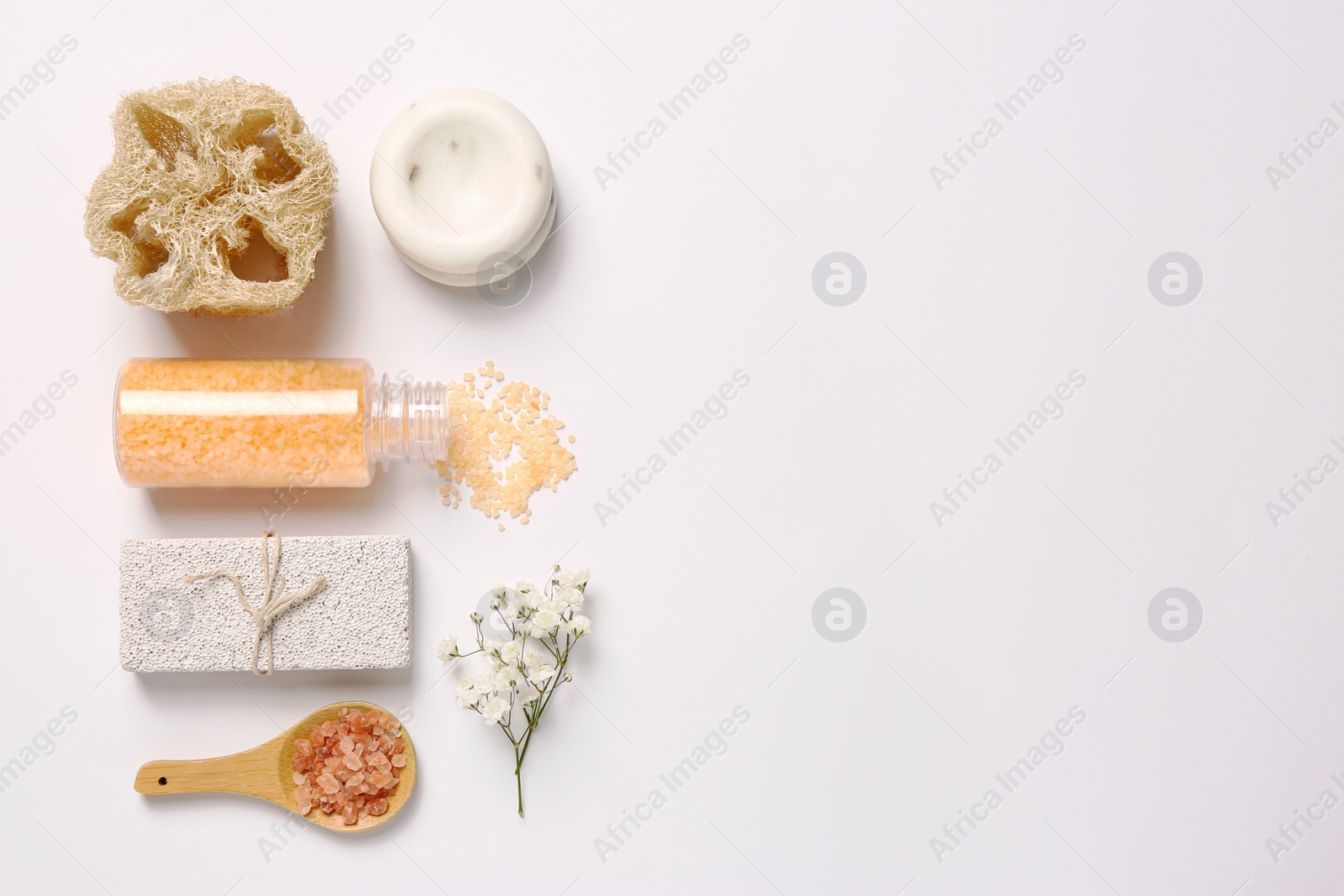 Photo of Sea salt, soap bar, beautiful flowers and loofah on white background, flat lay. Space for text