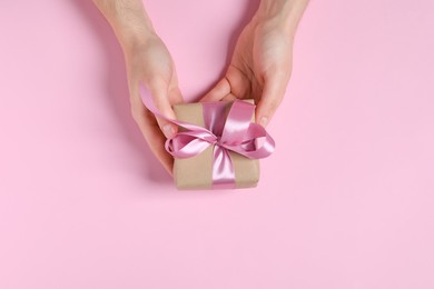 Man holding gift box with bow on pink background, top view