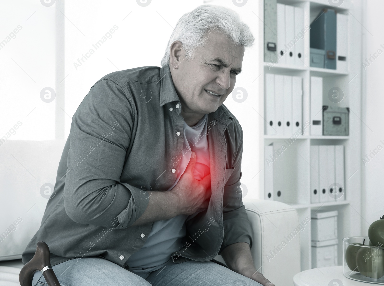 Image of Senior man having heart attack on sofa