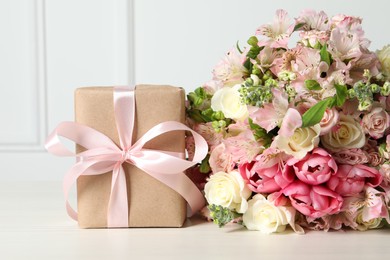 Photo of Happy Mother's Day. Gift box and bouquet of beautiful flowers on white table