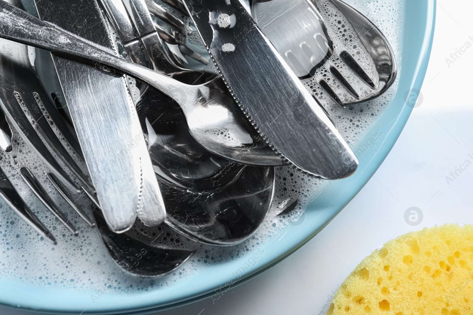 Photo of Plate with silverware in foam and sponge on white background, flat lay