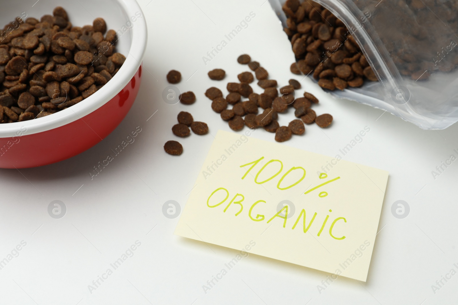 Photo of Pack and feeding bowl of dry cat food with note 100% Organic on white table