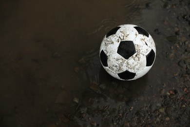 Photo of Dirty leather soccer ball in puddle outdoors, space for text