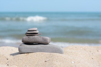 Stack of stones on sandy beach near sea, space for text