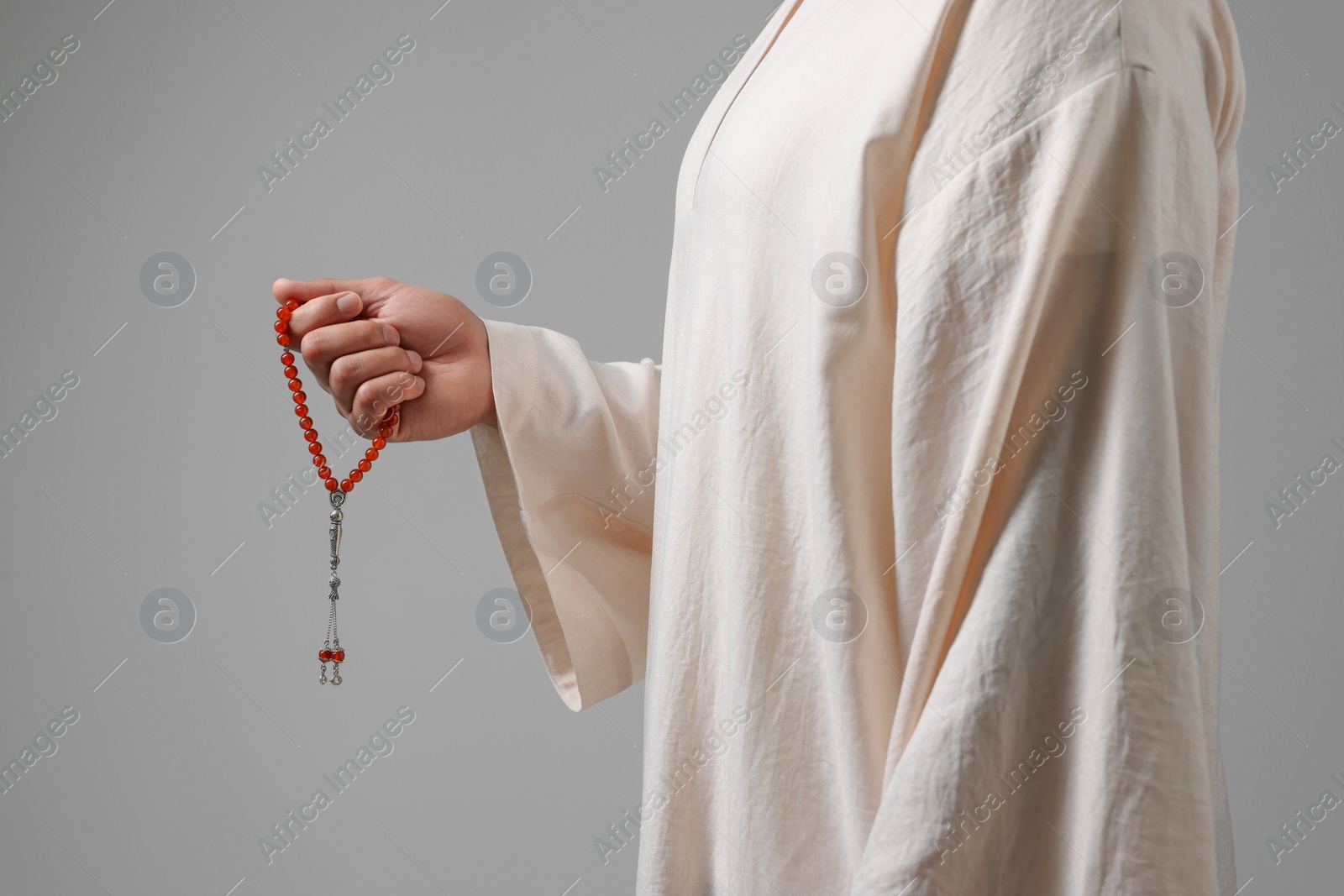 Photo of Muslim man with misbaha on light grey background, closeup