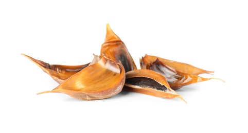 Unpeeled cloves of aged black garlic on white background