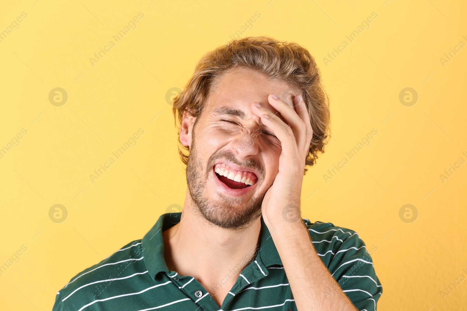 Photo of Handsome young man laughing on color background