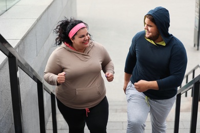 Photo of Overweight couple running up stairs together outdoors