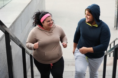 Overweight couple running up stairs together outdoors