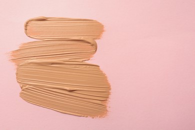 Photo of Sample of liquid skin foundation on pink background, top view. Space for text