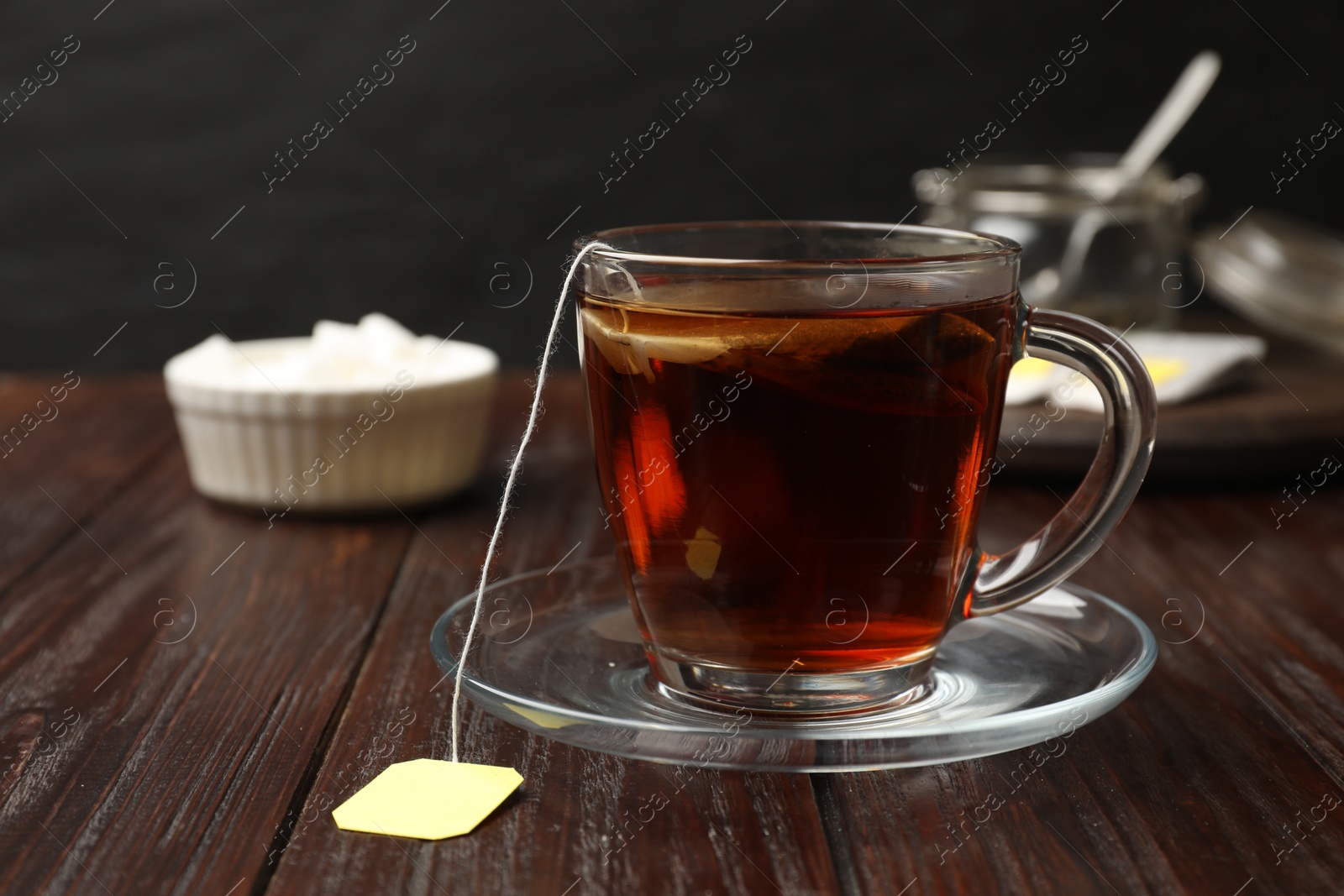 Photo of Brewing tea. Glass cup with tea bag on wooden table
