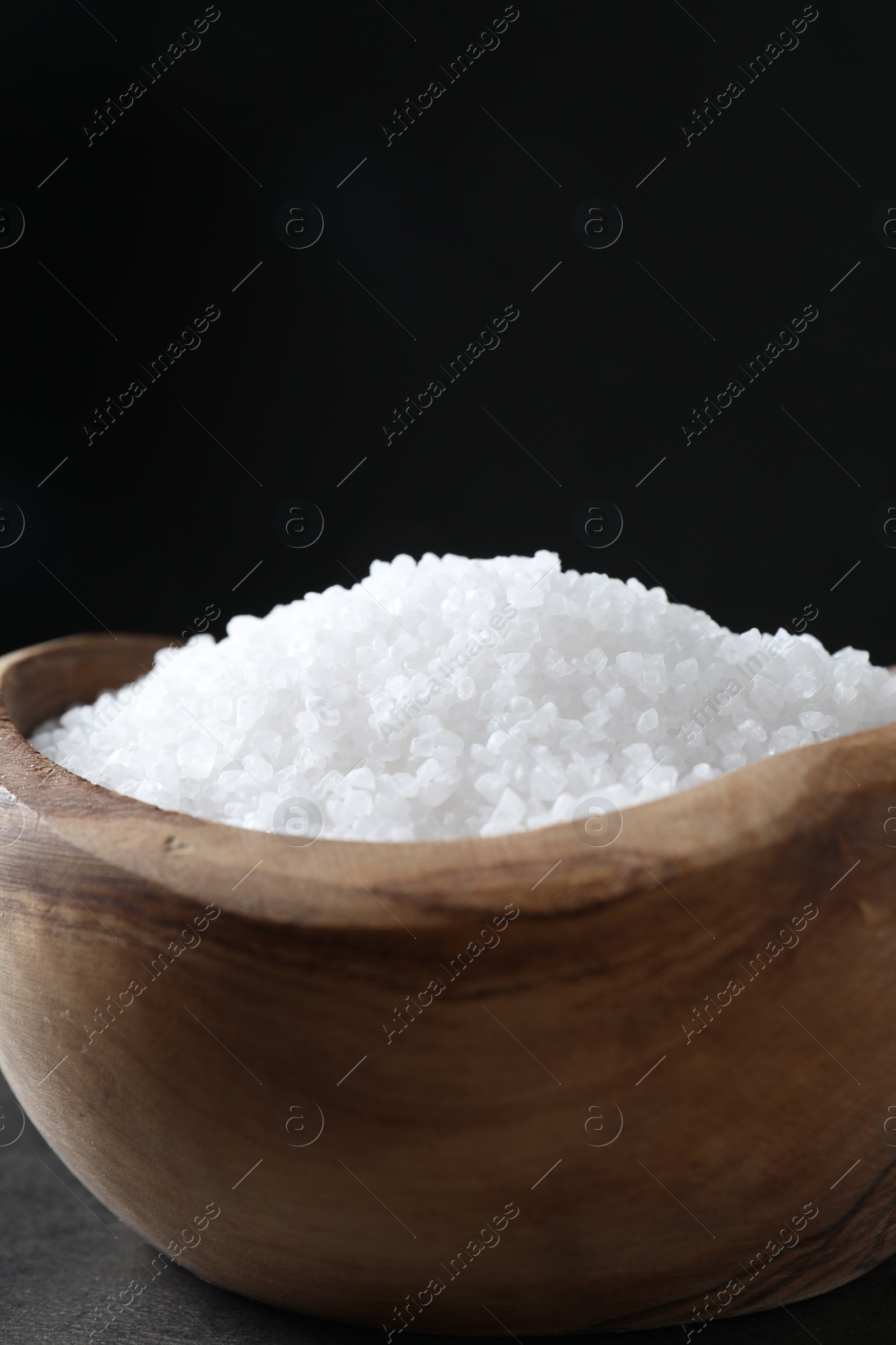 Photo of Natural salt in wooden bowl on table, closeup