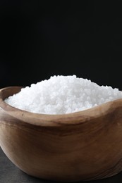 Photo of Natural salt in wooden bowl on table, closeup