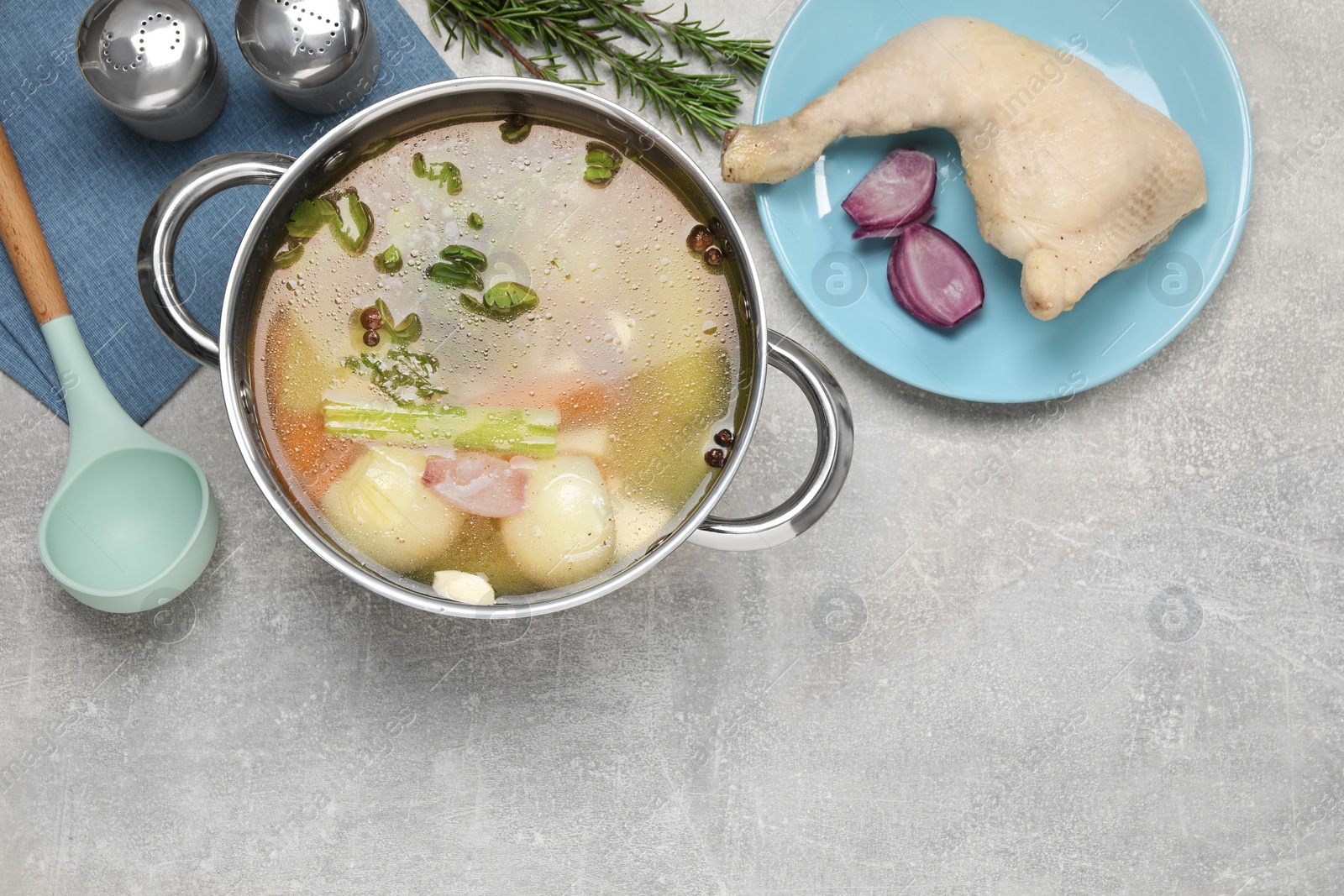 Photo of Pot with tasty bouillon and different ingredients on light grey table, flat lay. Space for text