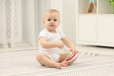 Children toys. Cute little boy playing with spinning top on rug at home