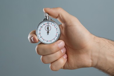 Man holding vintage timer on grey background, closeup